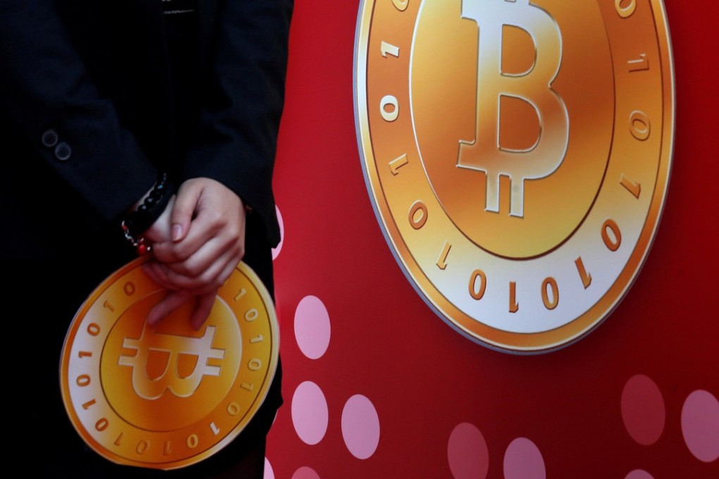 An attendant holds a bitcoin sign during the opening of Hong Kong's first bitcoin retail store February 28, 2014. PhotoL Reuters