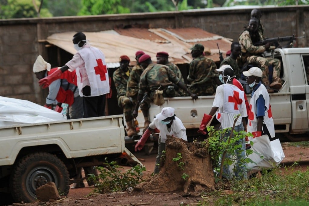 Red Cross workers retrieve bodies from the site of clashes in Bangui, in the Central African Republic, as rebels look on from a pickup truck, in 2013. Picture: AFP