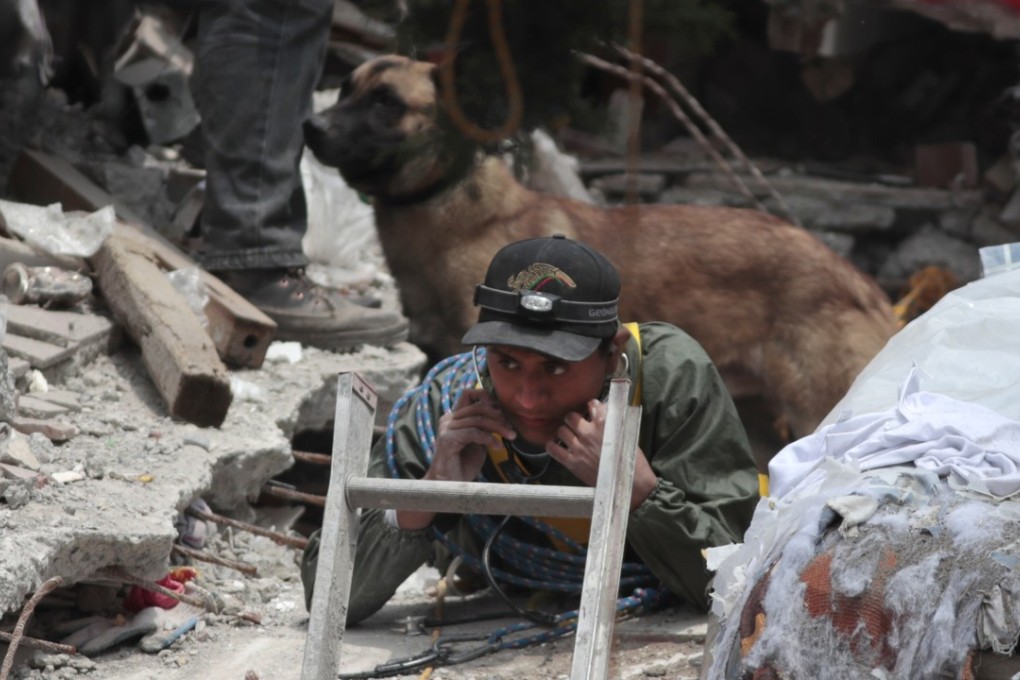 A rescue worker listens for signs of a person trapped under the rubble of a building in Mexico City on Thursday. Photo: AP