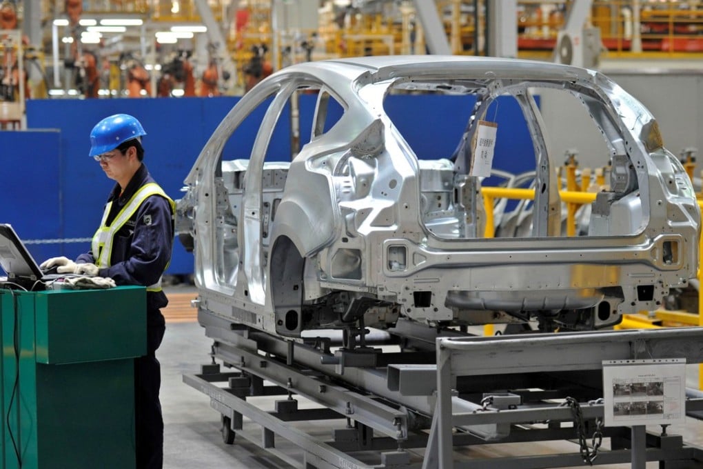 An employee uses a laptop next to a car body at an assembly line at a Ford manufacturing plant in Chongqing. Photo: Reuters