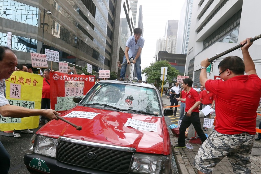 Drivers smash a taxi to call on the government to ban car-rental services, outside Wan Chai Tower in July 2015. Photo: Dickson Lee