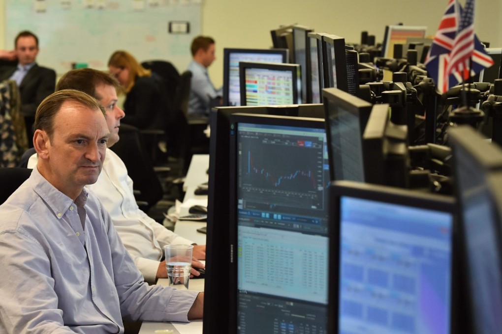 Traders work on the trading floor of ETX Capital in London. Moody’s recently highlighted the perils of Britain’s decision to leave the European Union by unexpectedly downgrading the UK’s rating. Photo: AFP