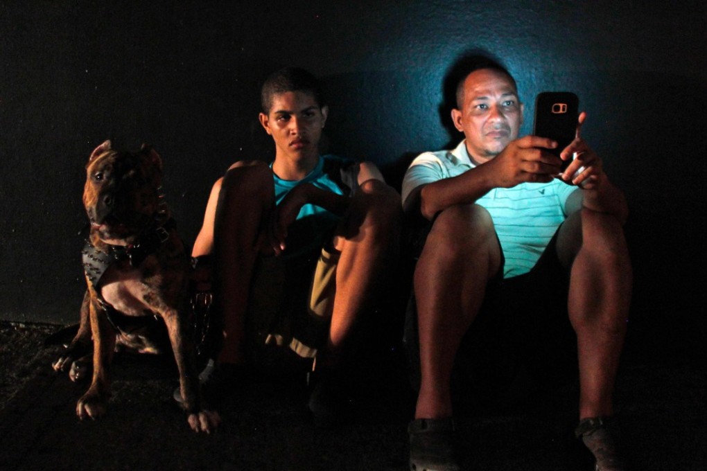 A man checks his mobile phone next to a road at night in one of a few places with cell signal in San Juan, Puerto Rico, on Monday. Photo: AFP