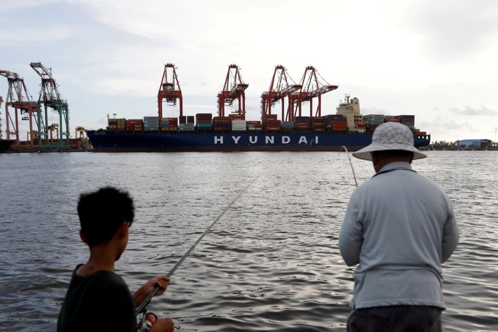 A boy and man fishing by a container ship at Kaohsiung port in Taiwan . Photo: Reuters