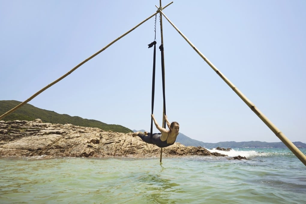 Bamboo Yoga founder Aleksandra Milewicz takes flight in her bamboo aerial yoga tripod over the clear blue waters of Sai Wan beach, Sai Kung. Photo: David Teng