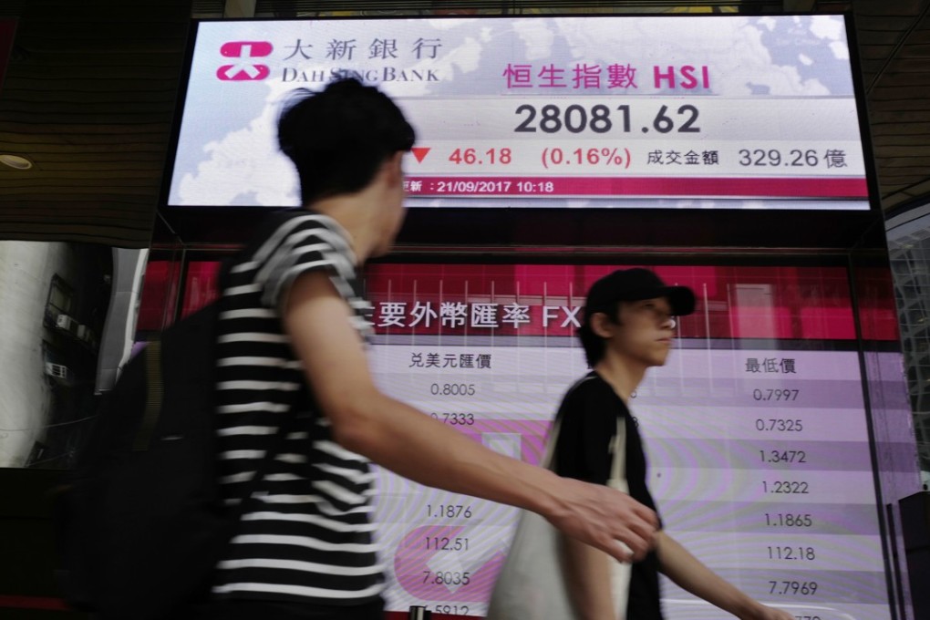 People pass by an electronic board showing Hong Kong share index outside a bank in Hong Kong. Buying of shares by company directors rose for a second straight week at the end of September. Photo: AP