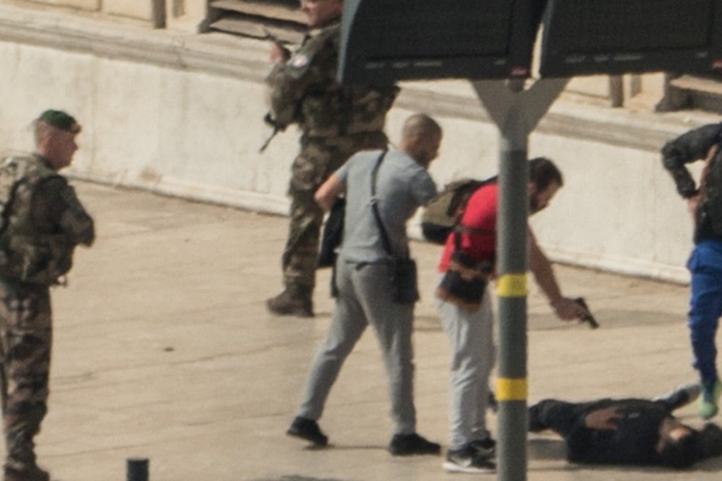 French police point a gun at a man on the ground while soldiers secure the area after the knife attack. Photo: AFP