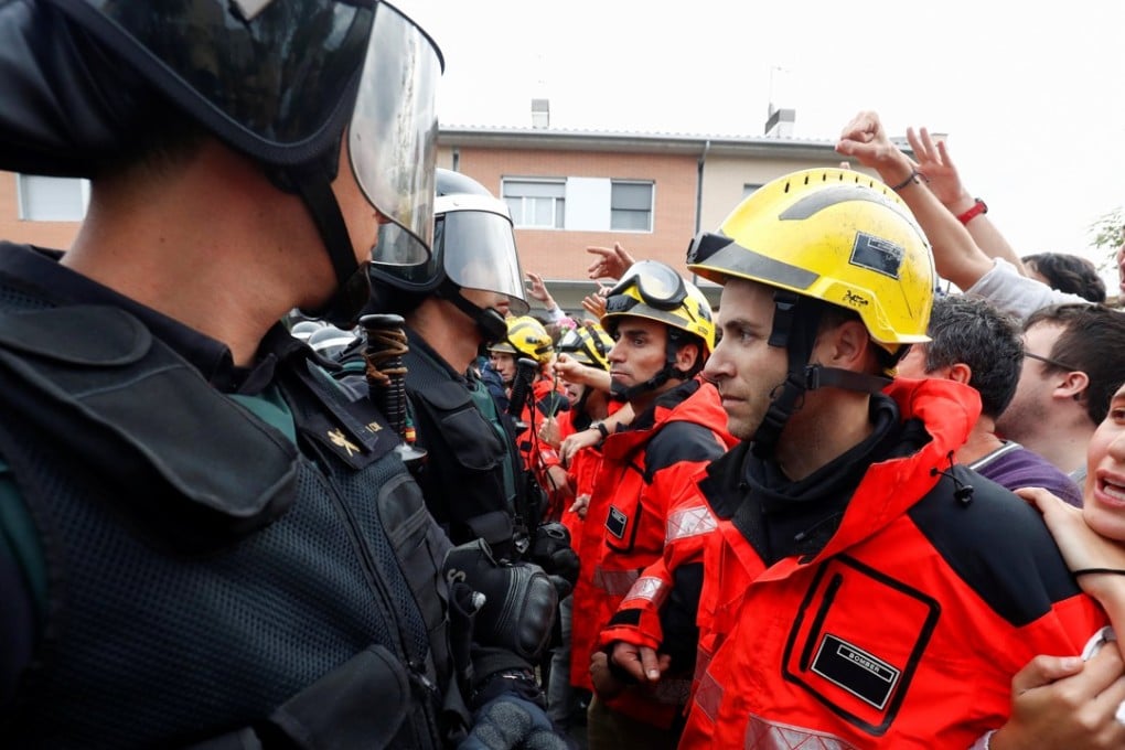 Firefighters stand between pro-independence Catalans and riot police at Sant Julia de Ramis sports centre near Girona on Sunday. Photo: Reuters