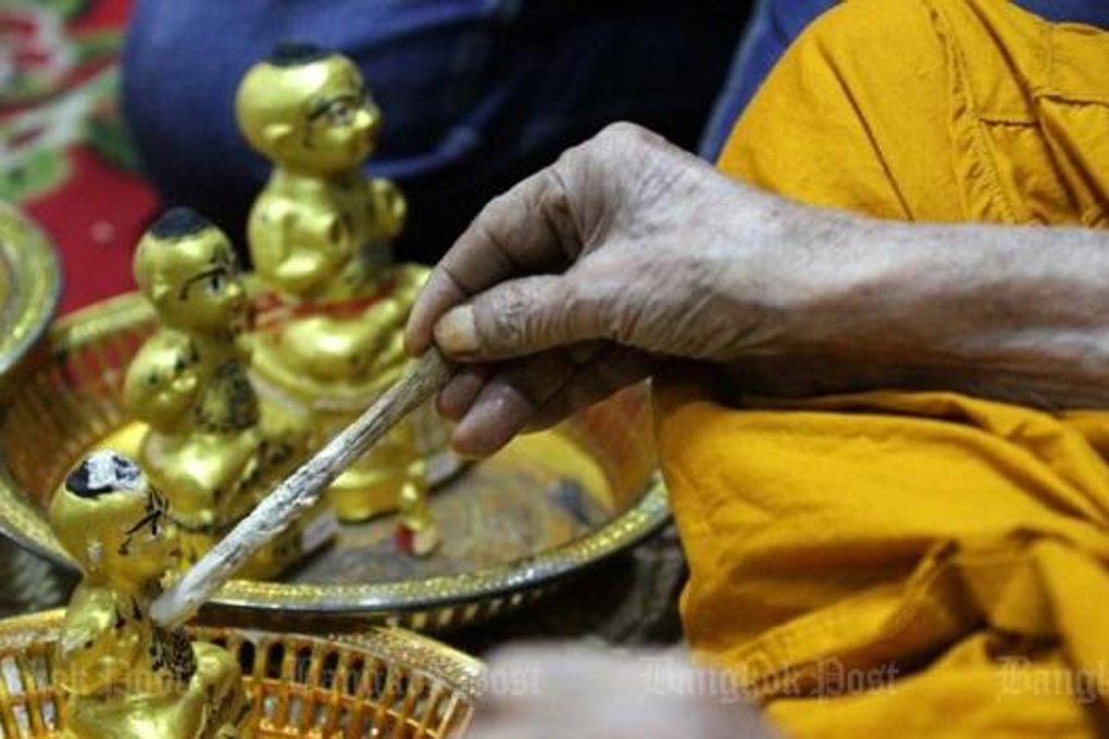 A monk consecrates a kumarn thong, a popular talisman many people believe has magical protective properties and can bring good fortune. Photo: Bangkok Post