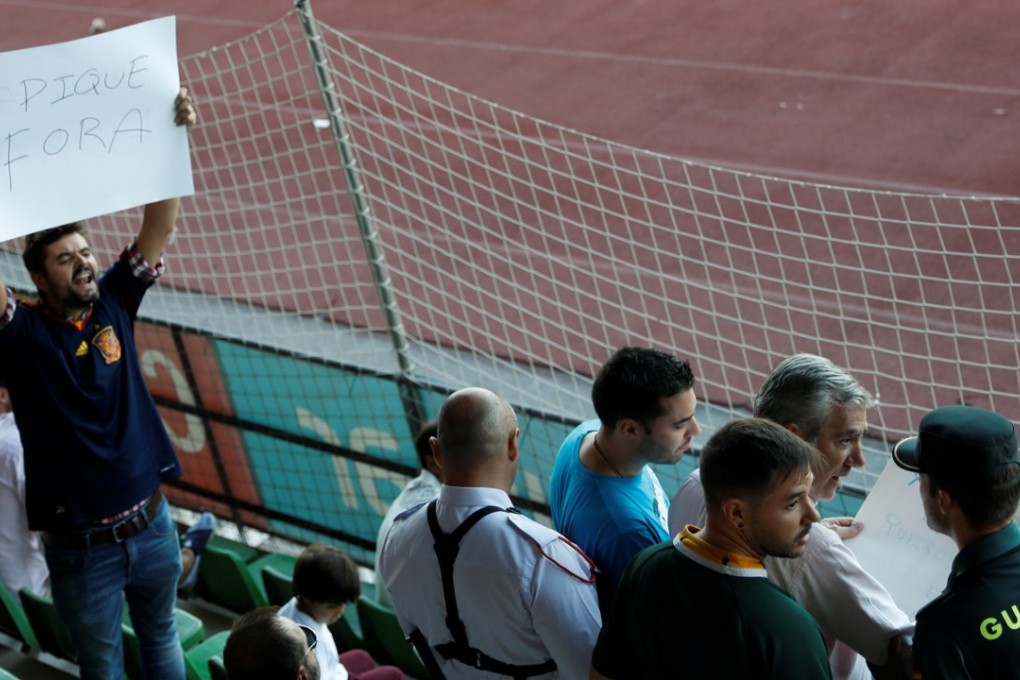 A Civil Guard officer removes a banner against Spain's player Gerard Pique as a man holds one that reads “Pique Out” before a training session in Las Rozas, near Madrid, Spain, October 2, 2017. REUTERS/Rafael Marchante