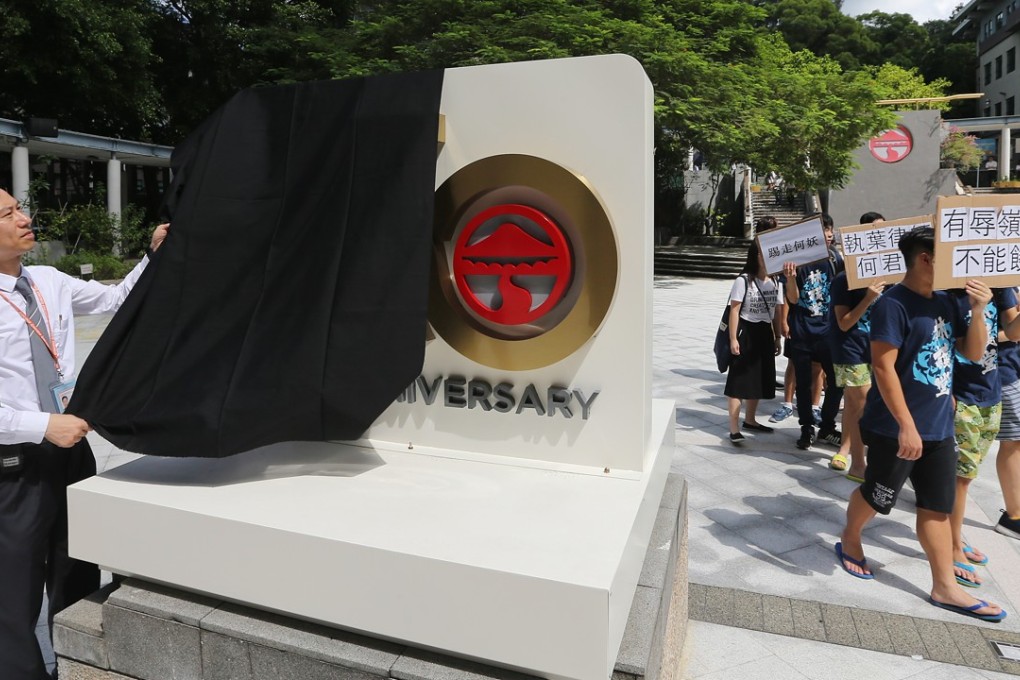 A security guard removes a black cloth from an emblem as Lingnan University students stage a protest against lawmaker Junius Ho Kwan-yiu. Photo: Sam Tsang