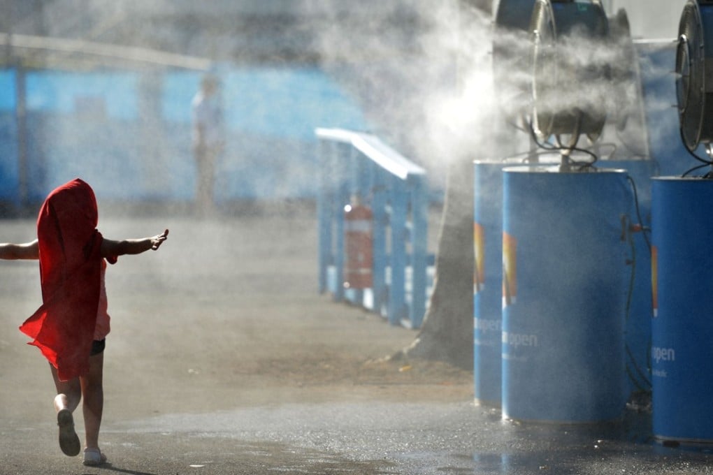 A young child cools off by running past a set of vapour fans in Melbourne. File photo: AFP