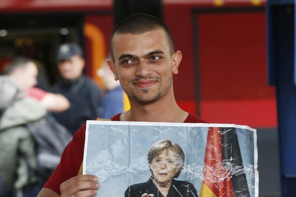 A refugee carries a picture of German Chancellor Angela Merkel as he arrives at the main train station in Munich. File photo: AP