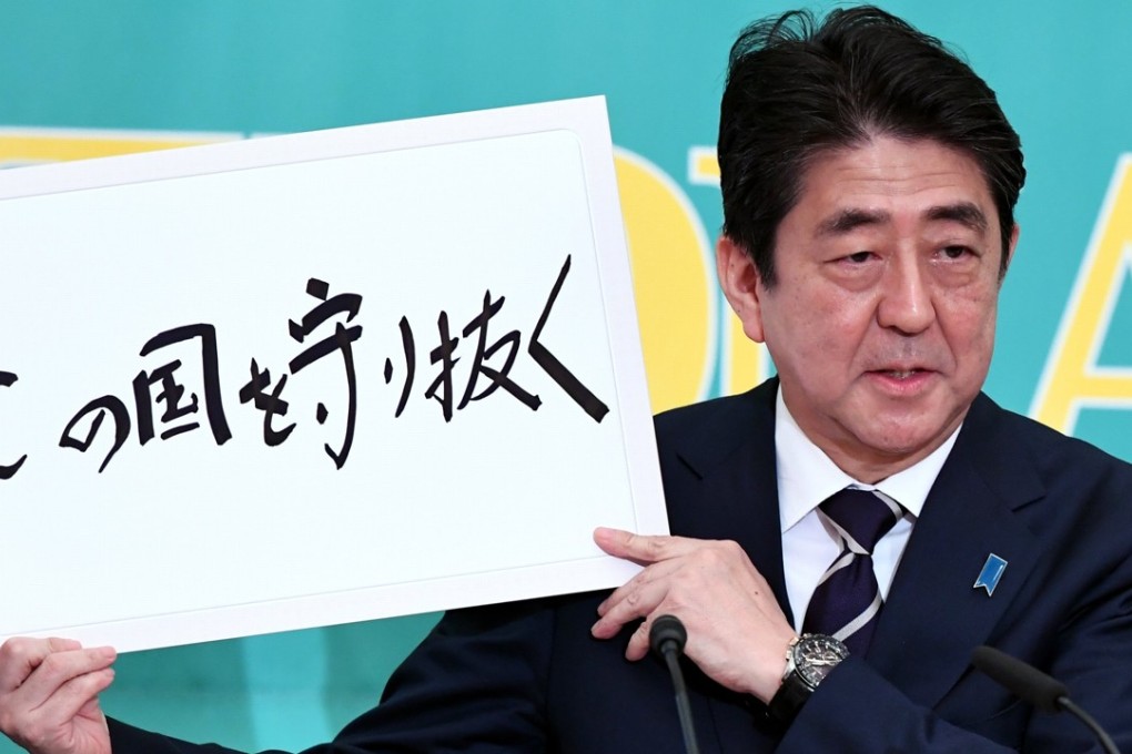 Japanese Prime Minister Shinzo Abe holds up a sign saying: ‘protecting this country’ during a televised debate with political party leaders. Photo: EPA