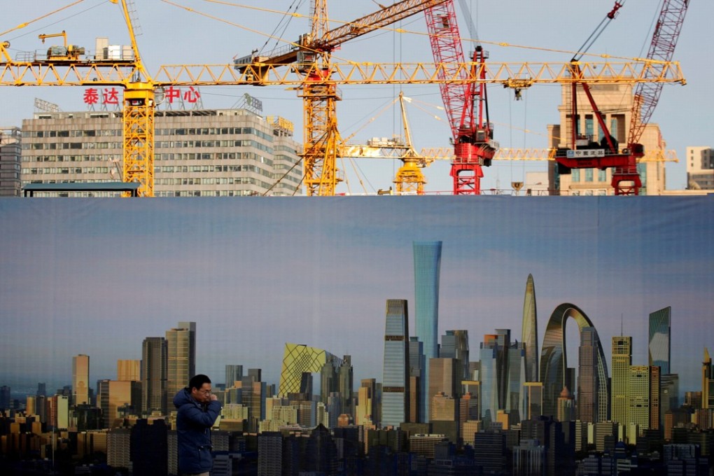 FILE PHOTO: A man walks past the hoarding of a construction site in Beijing (File Photo)