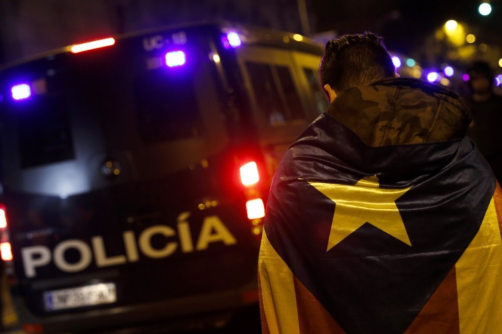 A Catalan independence supporter walks next to a police van in Barcelona on Tuesday. Photo: AFP
