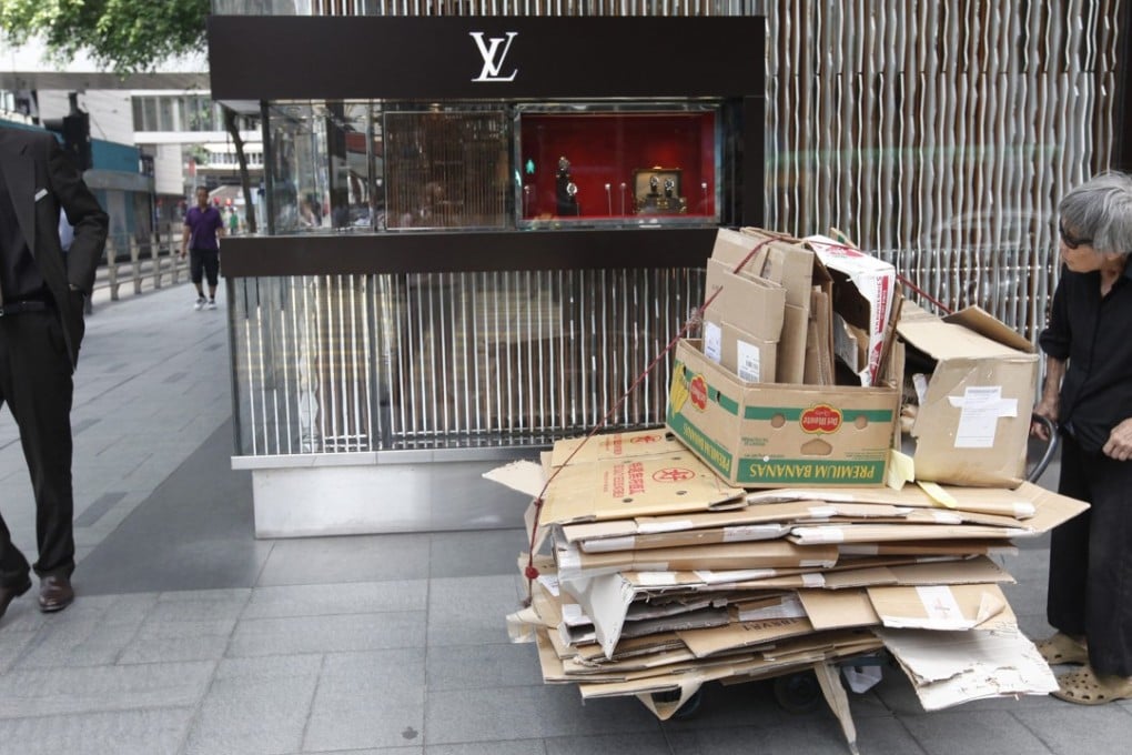 An elderly woman collecting scrap cardboard boxes to resell goes about her work outside the Louis Vuitton store in Central. Photo: EPA