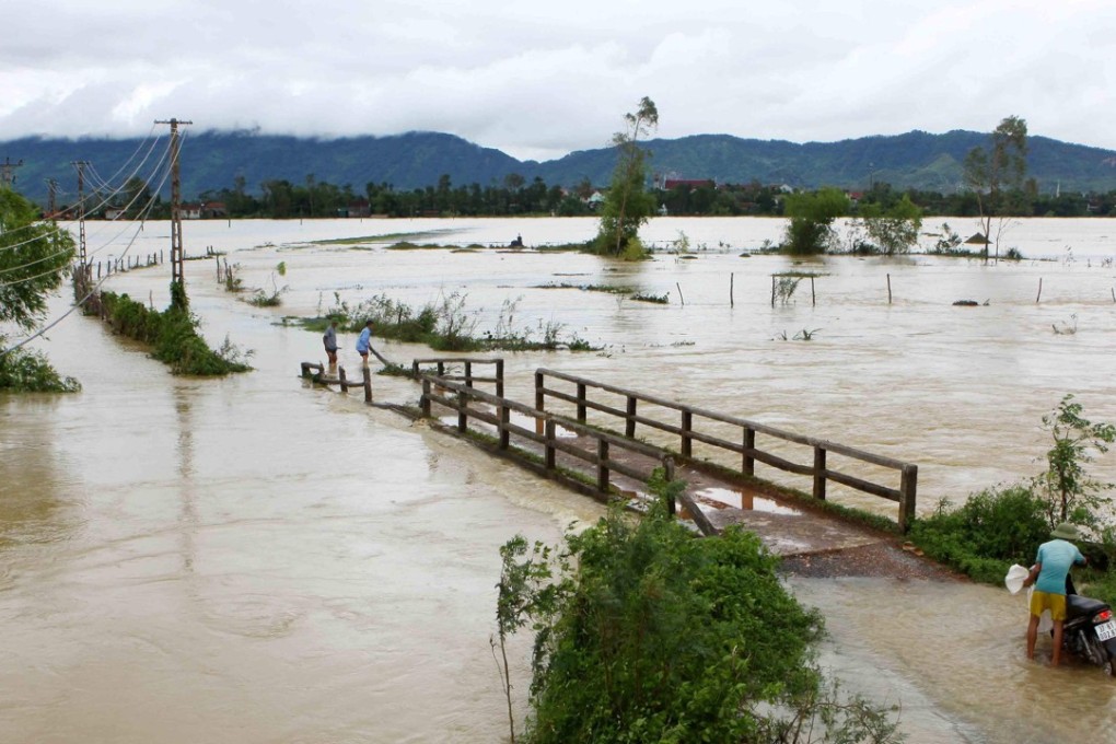 A man attempts to push his motorcycle through a flooded area in the central province of Nghe An. Photo: AFP