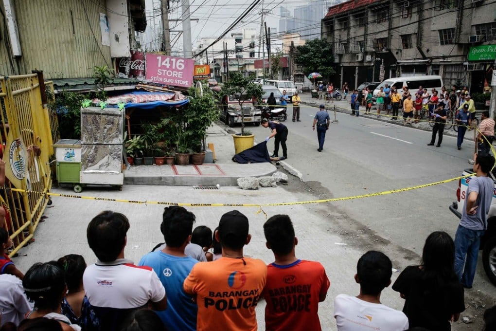 Locals look on as a police investigator checks the body of a man who was shot by unidentified gunmen in Makati. Photo: EPA
