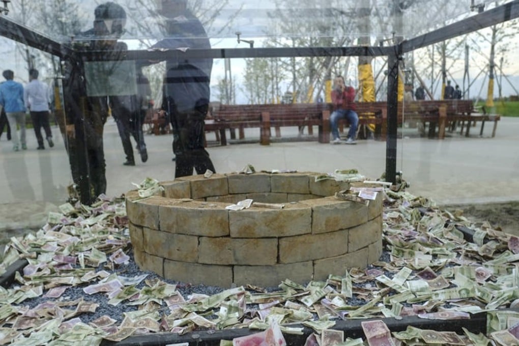 The case surrounding an ancient well that was put on display at a park in northwestern China was quickly filled with cash. Photo: Qq.com