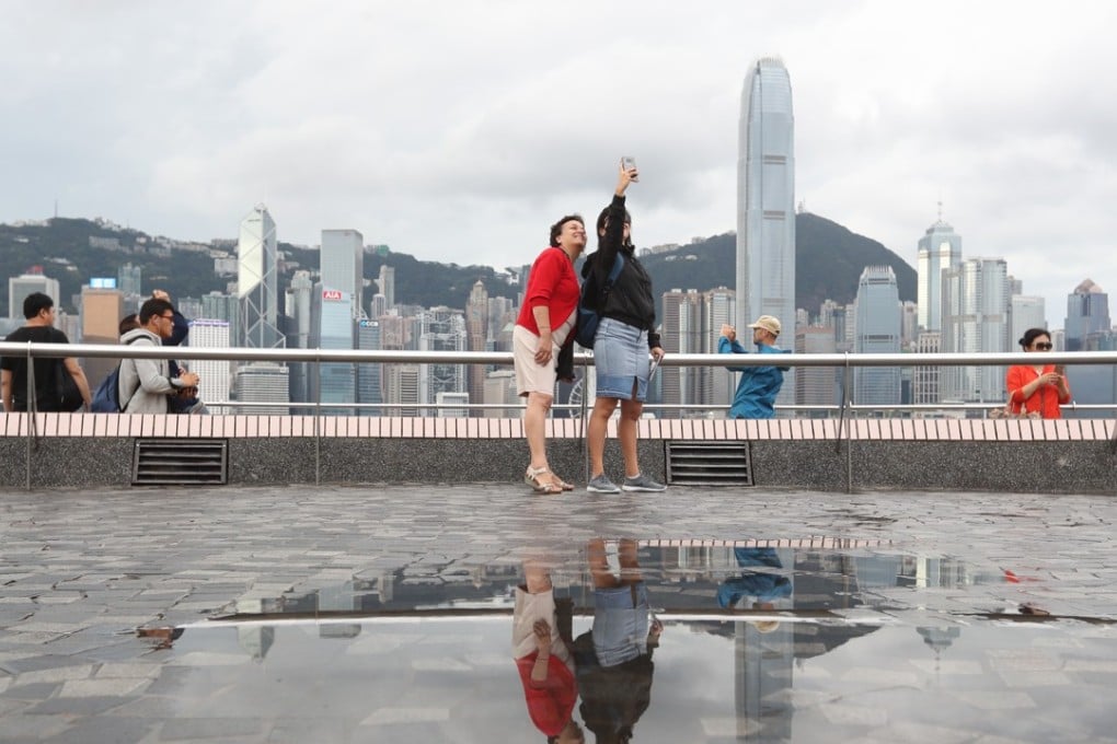 Tourists take pictures of Victoria Harbour from Tsim Sha Tsui on Sunday morning after the No 8 signal was issued. Photo: Edward Wong