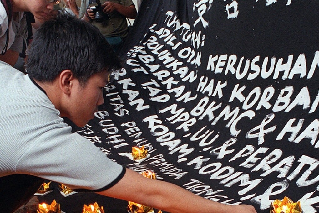 A young Chinese man puts a candle on a big banner in Jakarta during a ceremony in memory of victims of the 1998 riots. Photo: AFP
