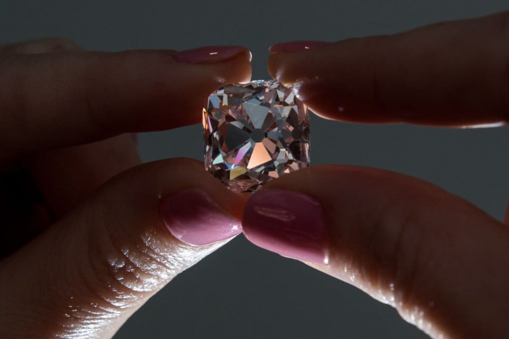A woman poses with the 'Le Grand Mazarin', a 19.07 carat pink diamond, at Christie's auction house in London on October 17, 2017. 'Le Grand Mazarin' is going to be sold at auction in Geneva on November 14, 2017. Photo: AFP