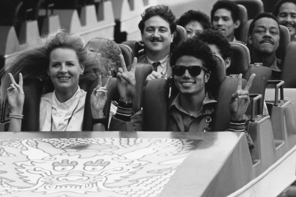 Michael Jackson, his minders and other visitors taking a roller coaster ride at Ocean Park. Entertainer Dr Penguin (with moustache) sits behind him.