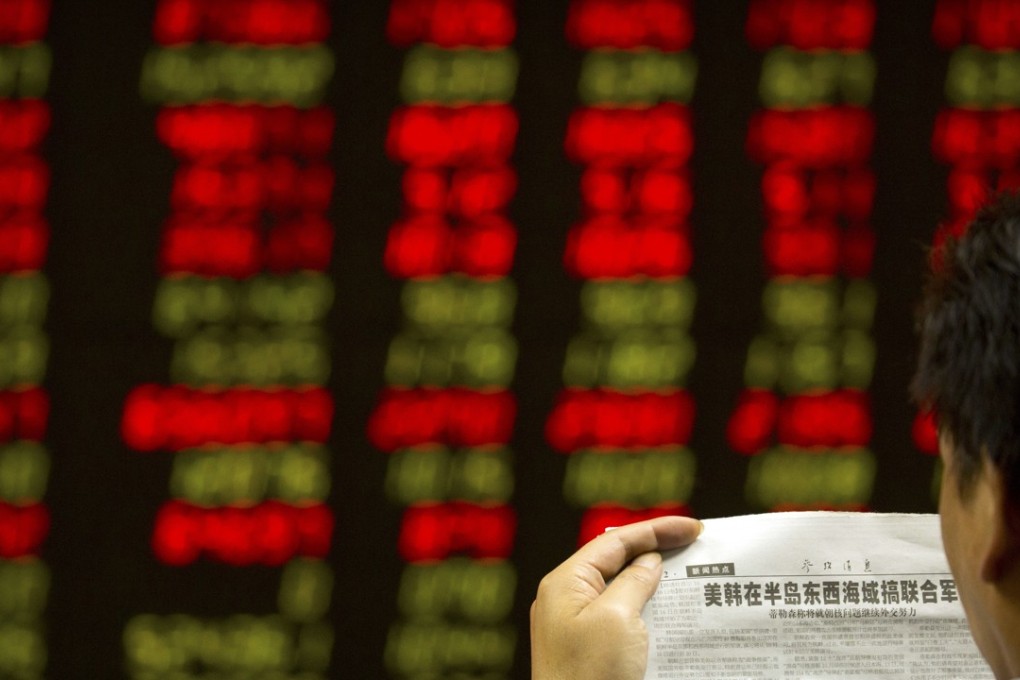 A Chinese investor reads a newspaper as he monitors stock prices at a brokerage house in Beijing. Photo: AP
