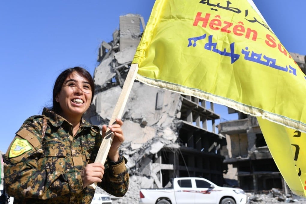 Rojda Felat waves an SDF flag at Paradise Square in Raqqa on Tuesday. Felat commanded thousands of troops during the liberation of the city. Photo: AFP