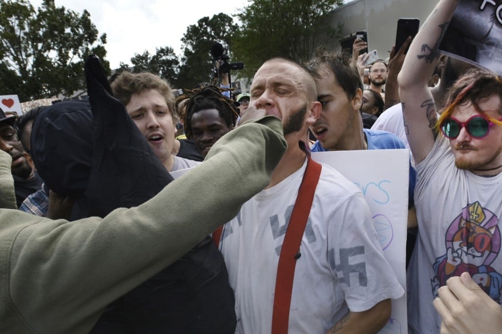 Skinhead Randy Furniss gets punched in the face as he walks through a crowd of protesters outside a University of Florida auditorium where white nationalist Richard Spencer was preparing to speak on in Gainesville. Photo: AP