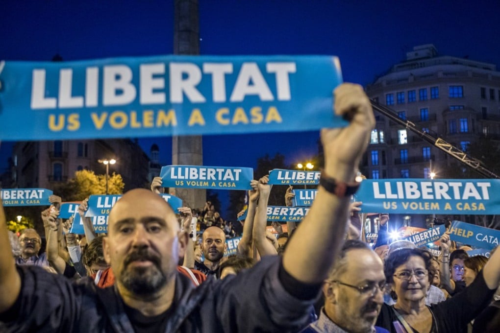 Protesters hold up banners reading “Help Catalonia” during a candlelight vigil to demand the release of imprisoned separatist leaders Jordi Sanchez, head of the Catalan National Assembly, and Jordi Cuixart, head of the Omnium Cultural association, in Barcelona, Spain, on October 17. Photo: Bloomberg