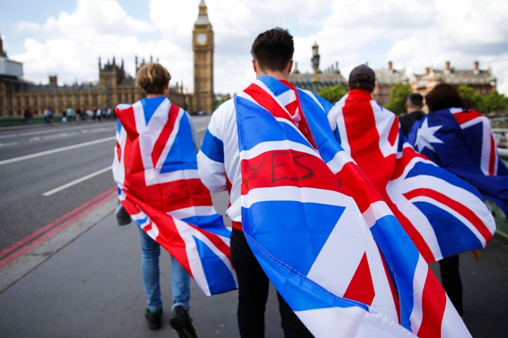 People walk over Westminster Bridge towards the Houses of Parliament in London wrapped in Union flags. Photo: AFP
