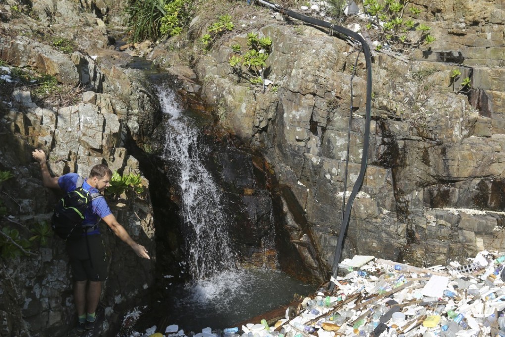 Paul Niel clings to a rock at a beach in the far corner of Big Wave Bay, in Shek O, looking at the amount of rubbish that has accumulated over the years, washed up from the ocean. Photo: Xiaomei Chen