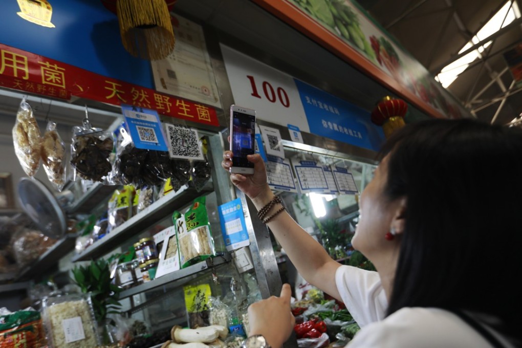 A woman scans an Alipay QR code to make a payment via her mobile phone in a market in Beijing, China, 09 August 2017. Even though it started late, China now has the world’s largest cashless economy, where two services -- Ant Financial’s Alipay and Tencent Holdings’ WeChatPay -- dominate the US$5.5 trillion market. Photo: EPA