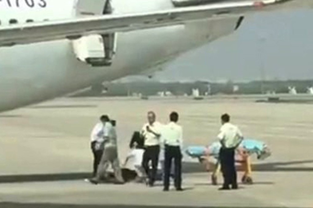 The woman is treated on the tarmac after falling out of the aircraft. Photo: Sina.com