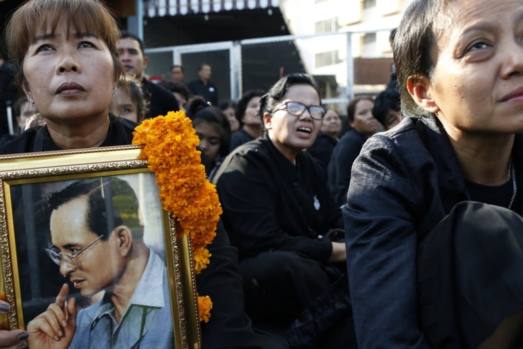 Thai mourners carry photos of late Thai King Bhumibol Adulyadej as they line up at the Royal Crematorium to attend the final cremation ceremony. Photo: EPA