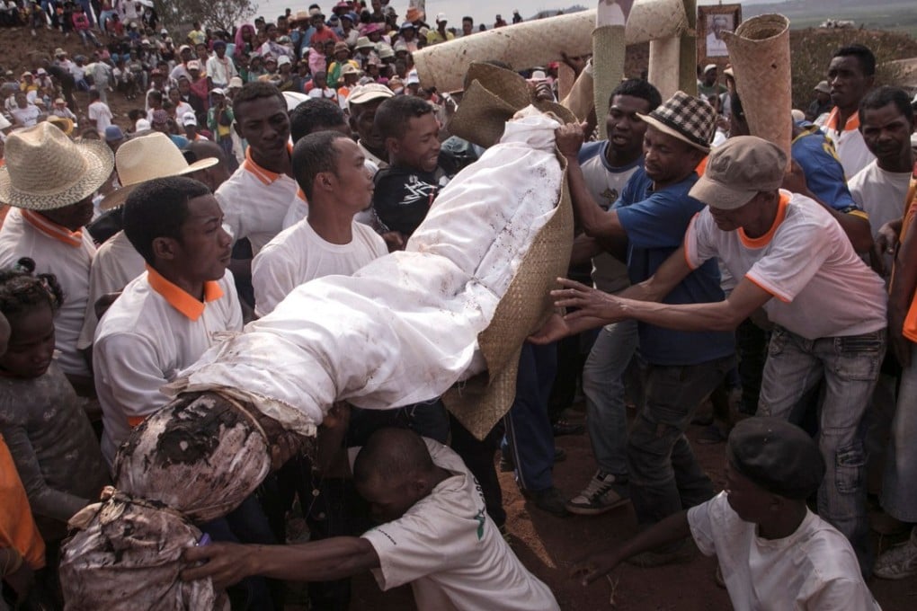 People carry a body wrapped in a sheet as they take part in a funerary tradition called the Famadihana in the village of Ambohijafy. Photo: AFP