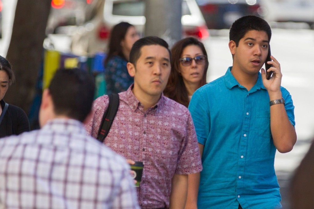 A pedestrian talks on his mobile phone on October 24, 2017 in Honolulu, Hawaii. The Honolulu Police Department will start enforcing The City and County of Honolulu's newest law against looking or texting on your mobile phone while using a pedestrian crossing. Photo: Agence France-Presse