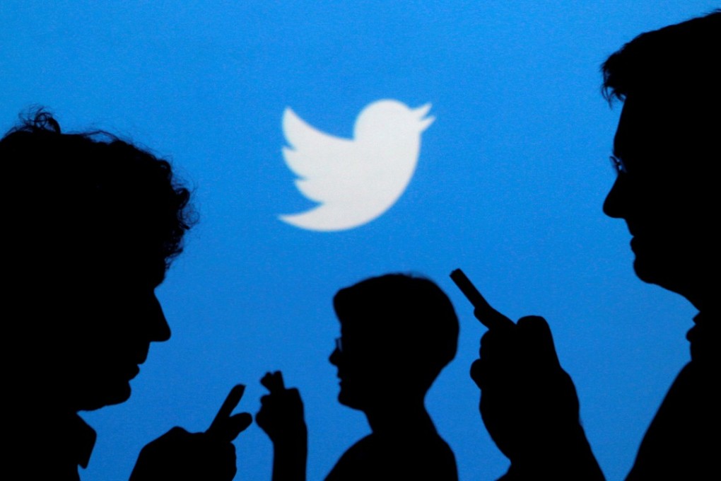 People holding mobile phones are silhouetted against a backdrop projected with the Twitter logo. Photo: Reuters