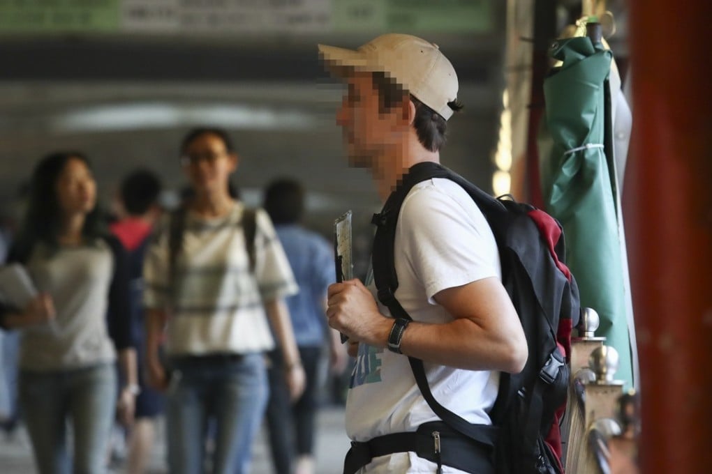 A Caucasian beggar tops up his travel kitty on a Hung Hom walkway. Picture: Nora Tam