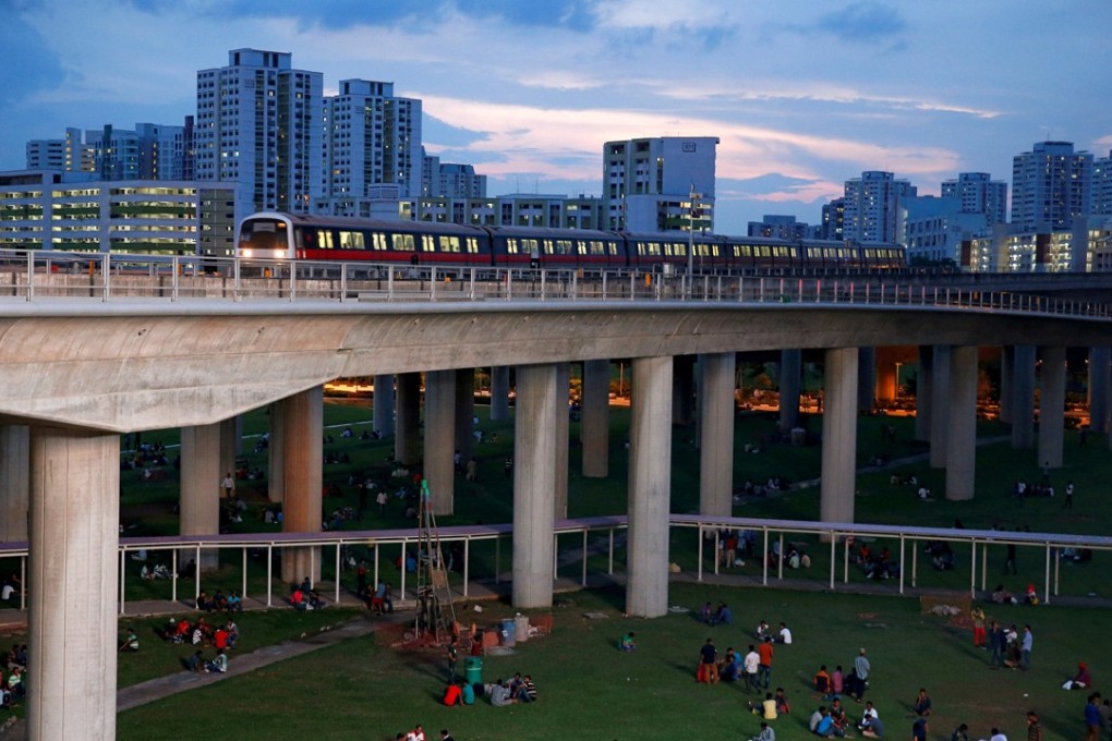 Migrant workers enjoy a day off near a train station in Singapore. Hong Kong’s MTR Corp enjoys greater economies of monopolistic scale than the two train operators in Singapore. Photo: Reuters