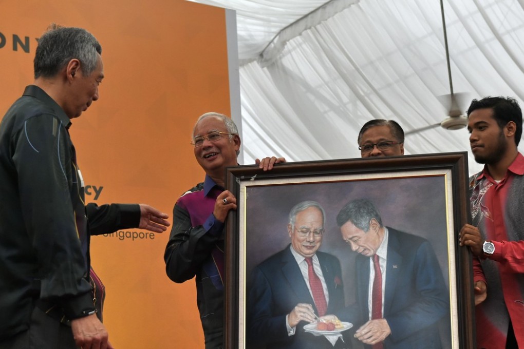 Malaysian Prime Minister Najib Razak hands to Singapore Prime Minister Lee Hsien Loong a painting of them both eating durian. Photo: AFP