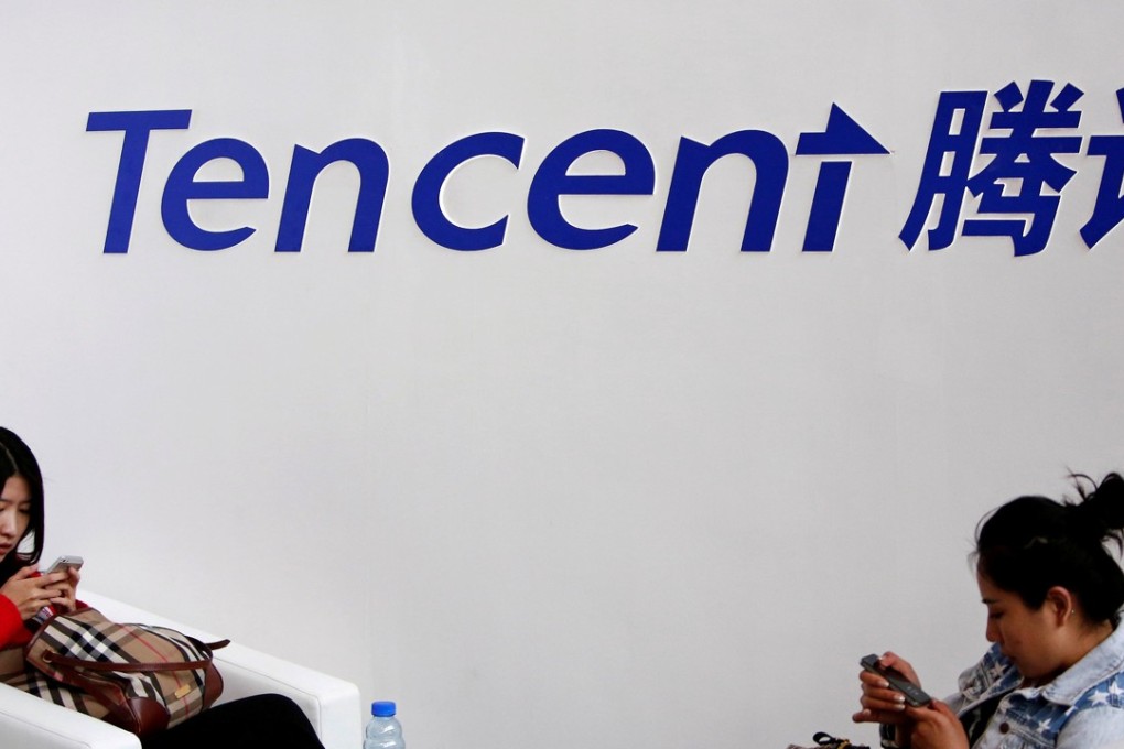 Visitors use their smartphones underneath the logo of Tencent. Photo: Reuters