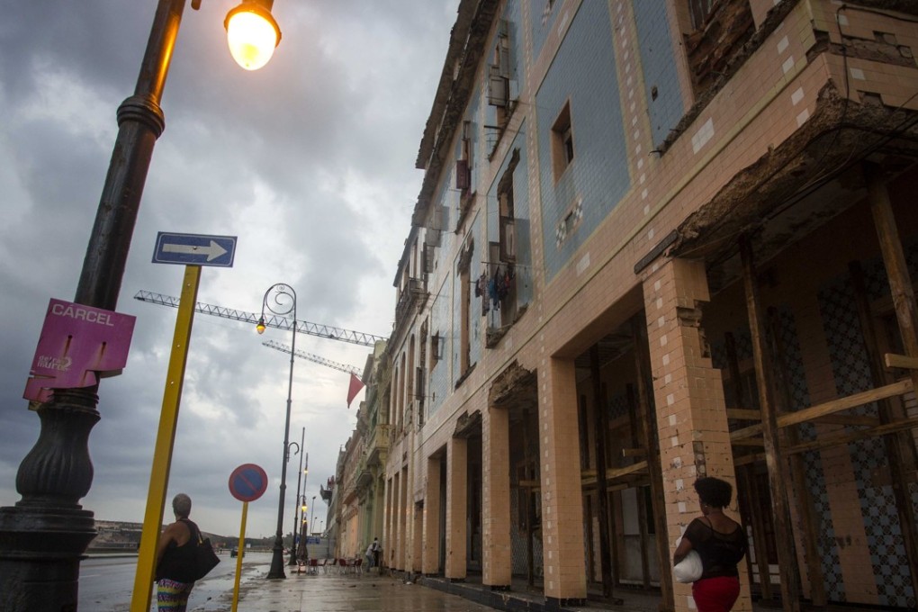 A woman walks by a damaged building on the Malecon, in Havana, Cuba. A tropical depression is headed for Cuba as tropical storm Selma hit El Salvador. Photo: AP