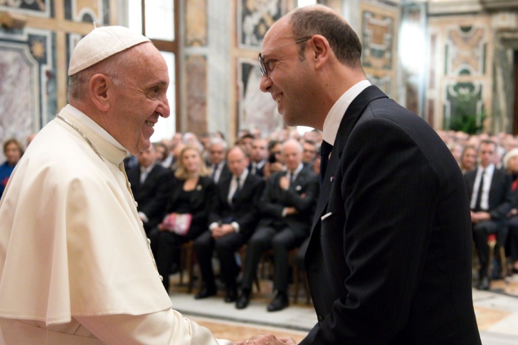Pope Francis (L) shaking hands with Italian Foreign Minister Angelino Alfano. Photo: Handout via Agence France-Presse