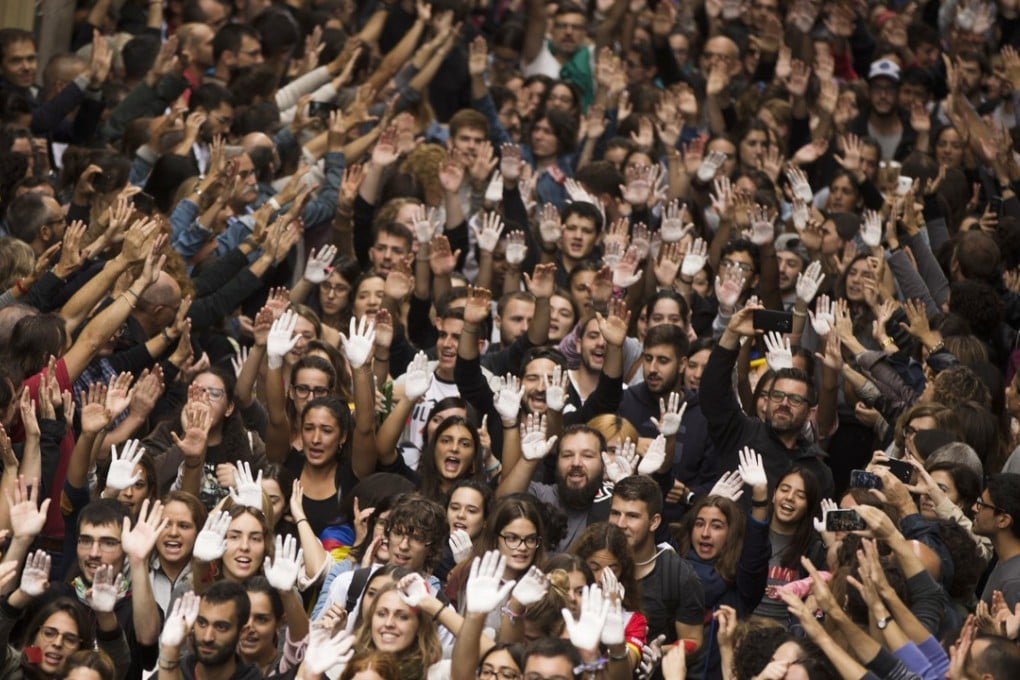 Catalan independence supporters raise their hands, some painted in white, as a symbol of protest, as they shout slogans during a rally outside the city hall of Girona on October 2. Photo: AP