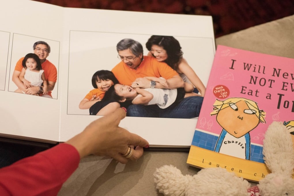 Wee looks through a family photo album. Beside it are her late daughter Zoe’s favourite story book and toy bunny. Picture: AFP