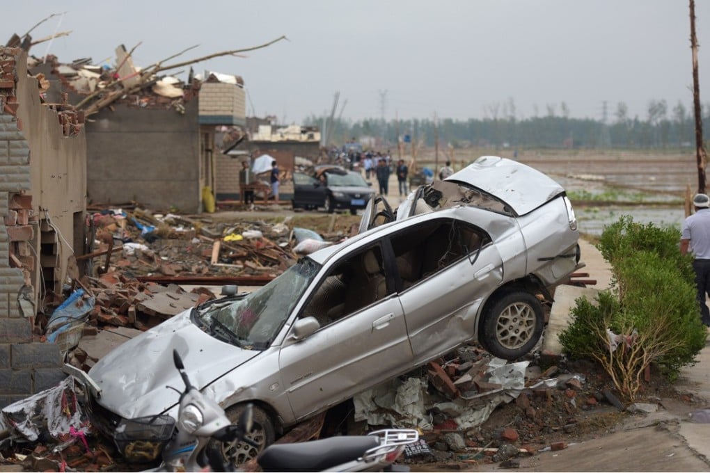 Residents walk in the rubble of destroyed houses after a tornado in Funing, in Yancheng, in China's Jiangsu province. Extreme weather caused some US$129 billion in economic losses last year, said a report Tuesday that warned the bill will keep climbing as climate change boosts droughts, storms and floods. File photo: AFP