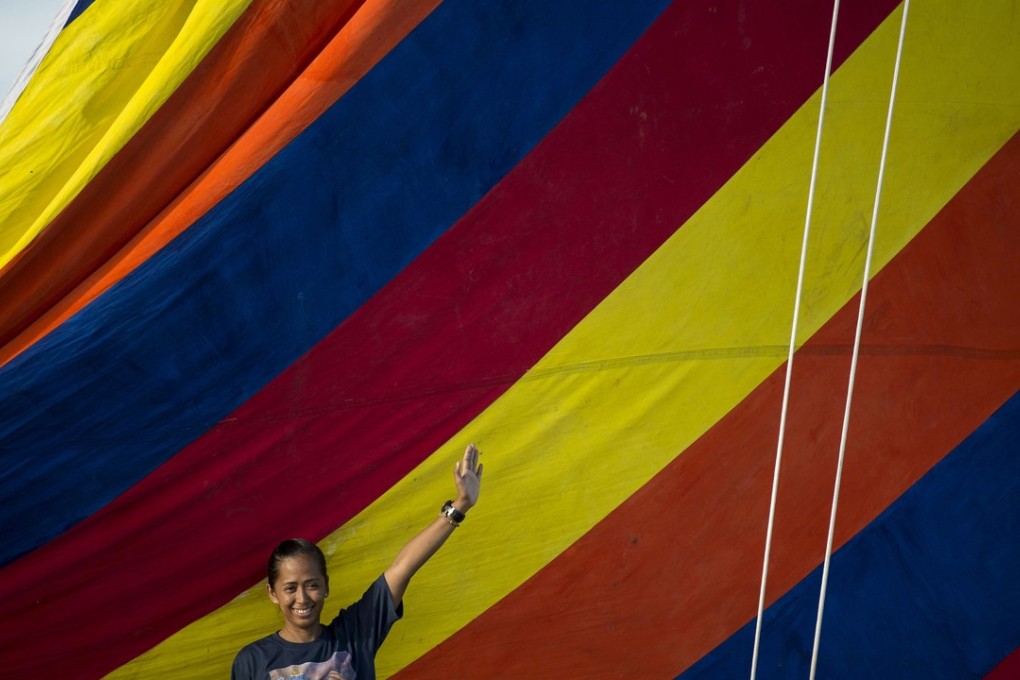 Philippine adventurer Carina Dayondon waves aboard a traditional Philippine wooden boat known as balangay, in Manila Bay. Photo: AFP